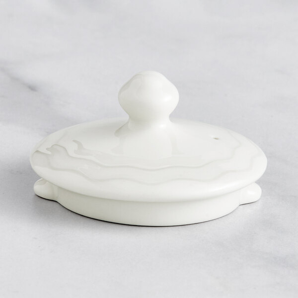 A white RAK Porcelain lid with an embossed floral design.