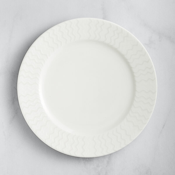A RAK Porcelain ivory flat plate with wavy lines on the rim.