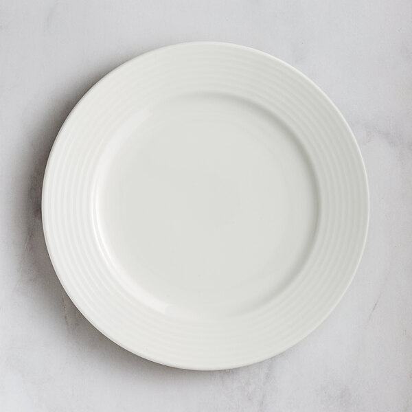 A RAK Porcelain ivory embossed porcelain plate with wide rim on a marble surface.