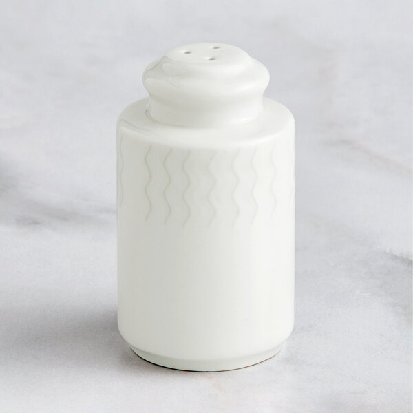 A close-up of a white RAK Porcelain salt shaker on a marble surface.