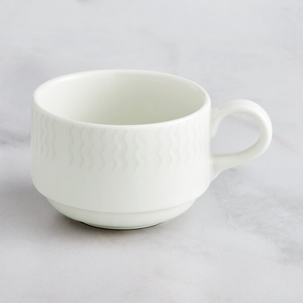 A RAK Porcelain ivory stackable cup with a handle on a marble surface.