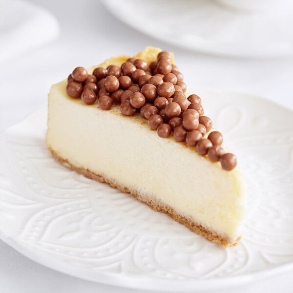 A slice of cheesecake with Mona Lisa milk chocolate crispearls on top.