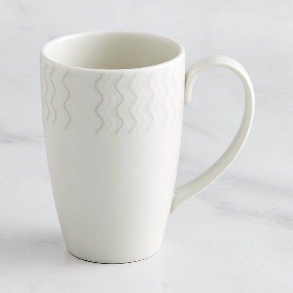 A white RAK Porcelain Flora mug with an embossed design on it and a handle.
