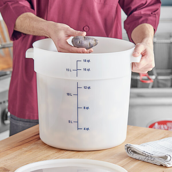 A man using a measuring cup in a large white container.