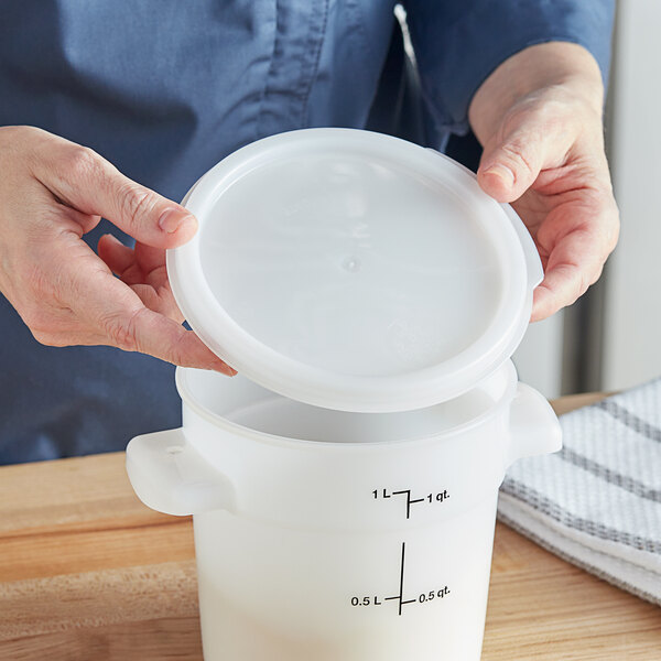 A woman holding a white plastic container with a white plastic lid.