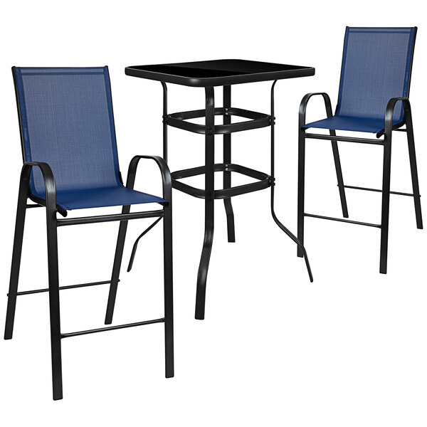 An outdoor glass bar table with navy chairs on an outdoor patio.