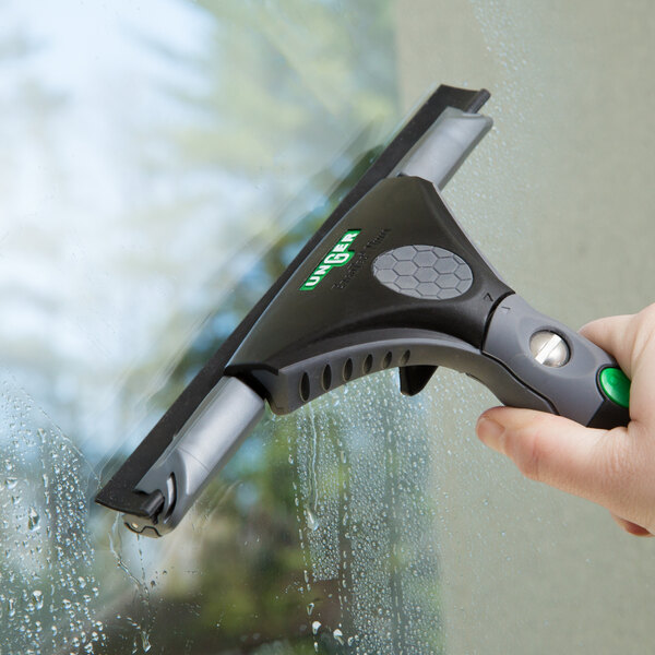 A hand holding a Unger ErgoTec Ninja squeegee cleaning a window.