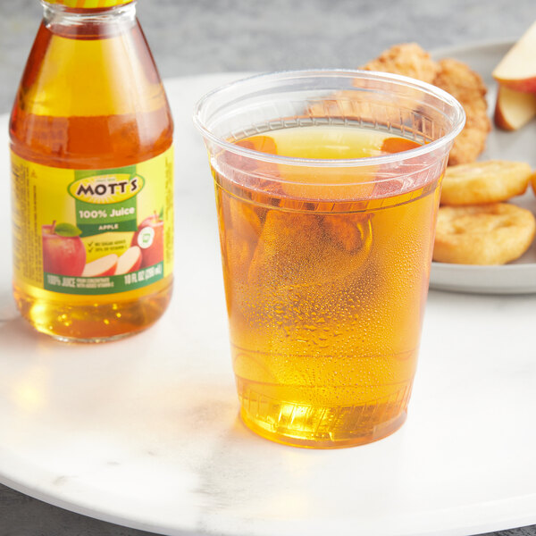 A glass of Mott's apple juice next to a plate of food.
