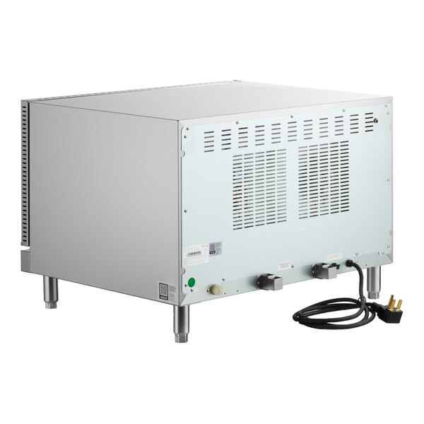 A stainless steel countertop appliance with vented panels, four metal legs, and a power cord with a three-prong plug visible at the back.