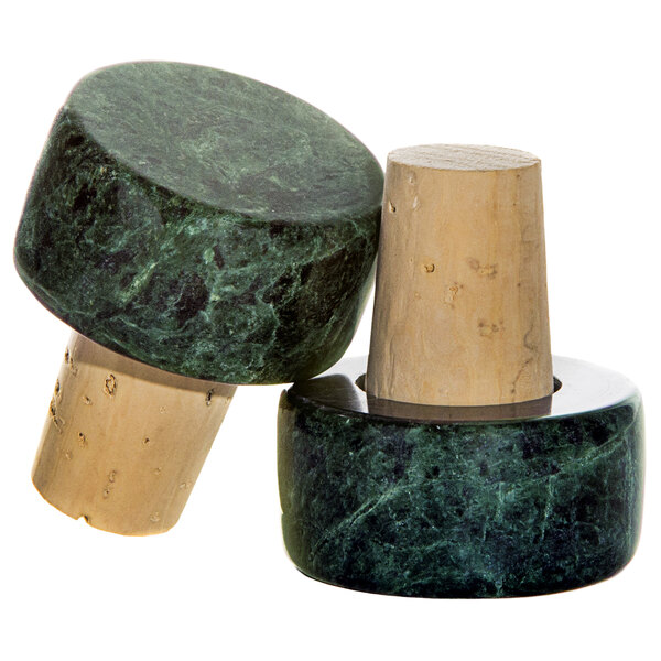 Two Franmara green marble wine stoppers with wooden stems on a counter.