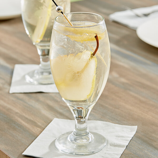 A glass of Pure Craft Beverages Ginger Pear beverage concentrate in water with a stick of pear.