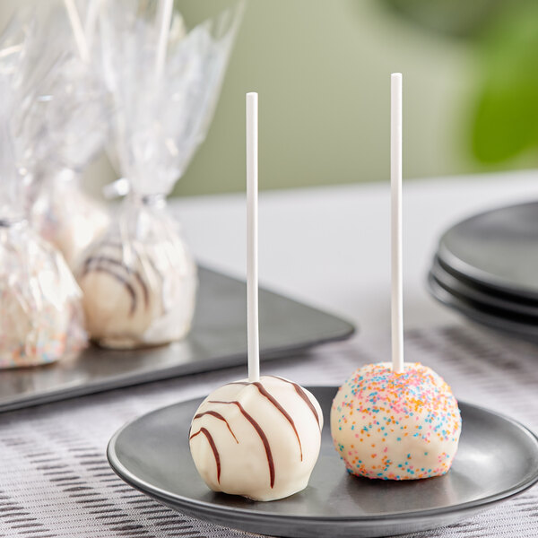 Individually wrapped white Chalet Desserts cake pops on a plate with sprinkles.