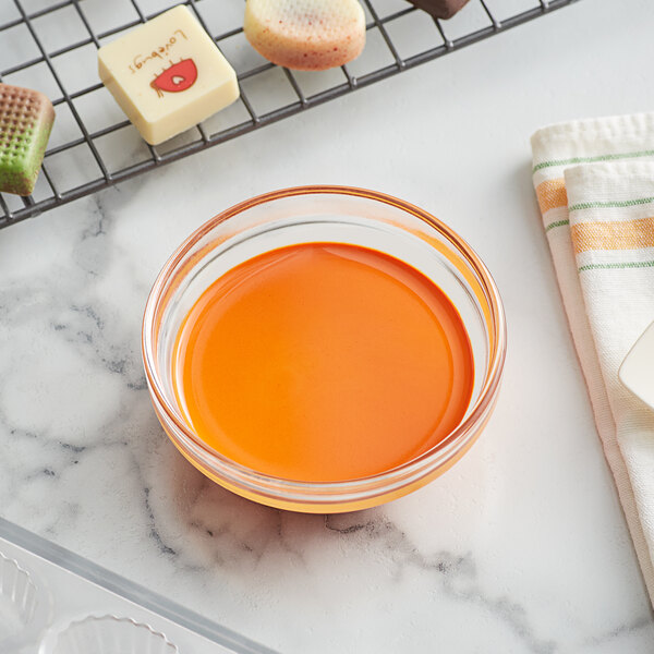 A bowl of orange liquid next to some baking ingredients.