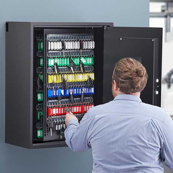 A man looking at a large black steel 360 Office Furniture key cabinet.