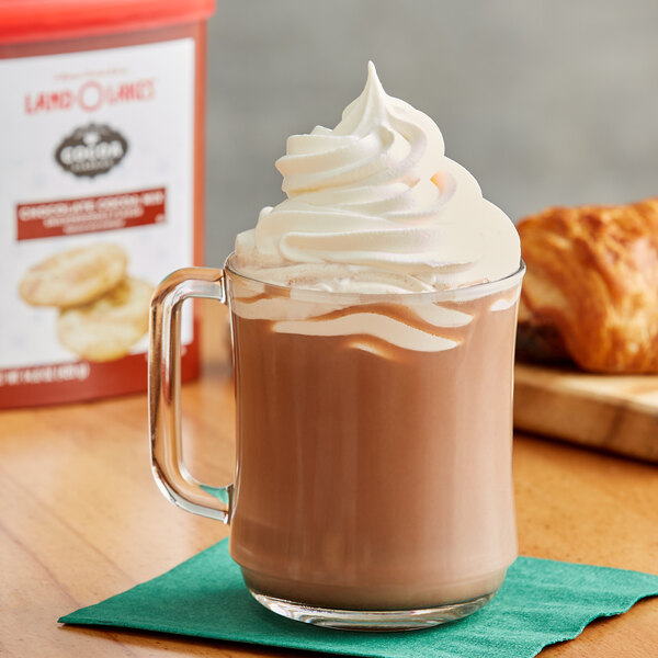 A glass mug of Land O Lakes Cocoa Classics Chocolate Snickerdoodle hot cocoa with a croissant on the side.