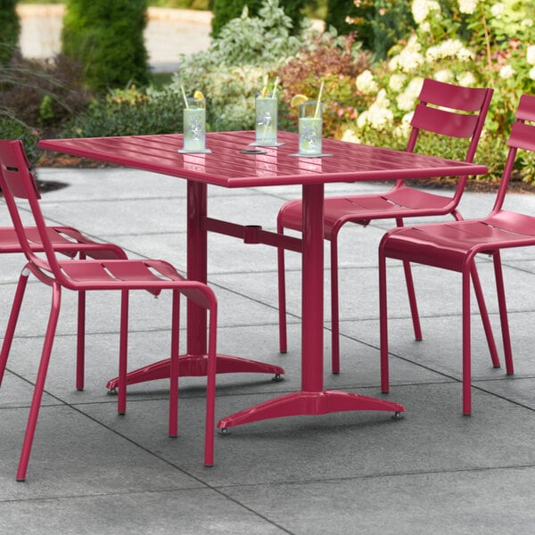 A red Lancaster Table & Seating outdoor table with chairs on a patio.