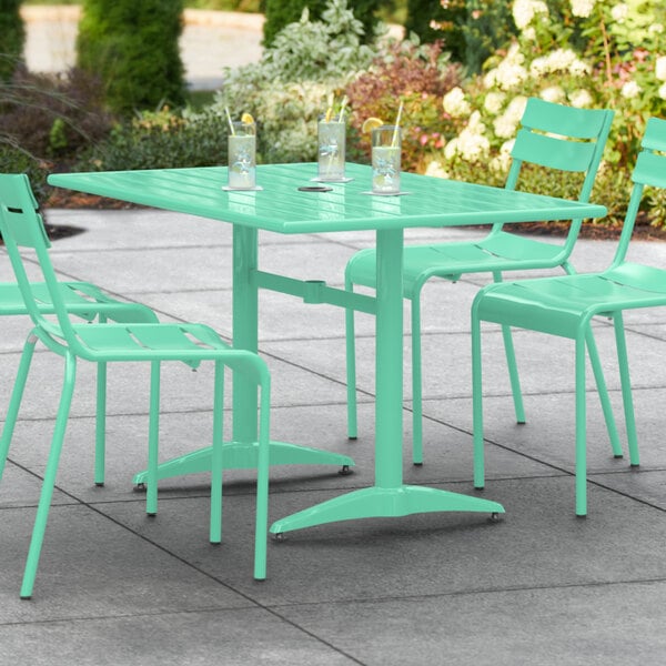 A Lancaster Table & Seating sea foam green table with chairs on a patio.