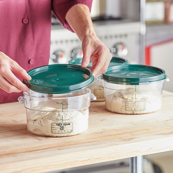 A woman using a Vigor clear plastic container with a green lid to store white dough.