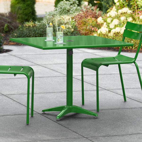 A green Lancaster Table & Seating dining table on a patio with two chairs.