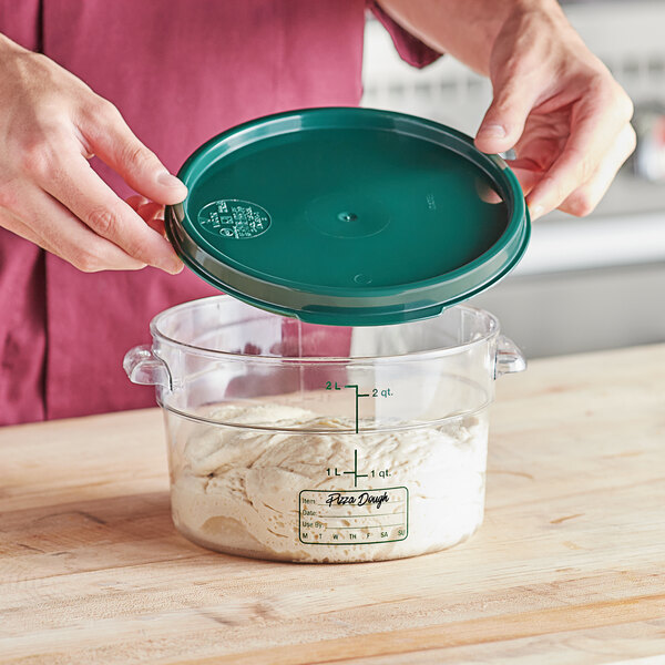 A person holding a green lid over a clear container.