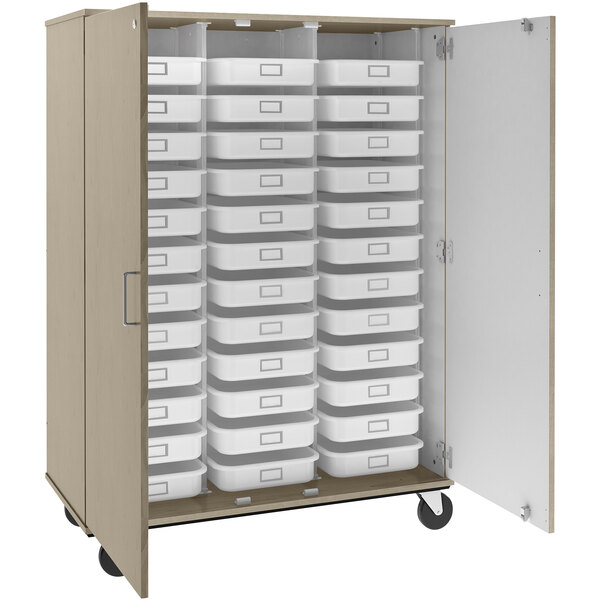 A tall natural elm I.D. Systems mobile storage cabinet with many trays and bins inside.
