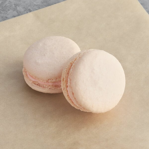 A pink and white macaron sitting on a piece of paper.