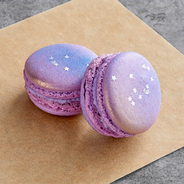 Two purple and blue Macaron Centrale Neptune macarons on a brown surface.