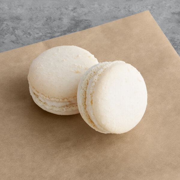 Two white Macaron Centrale coconut macarons on a brown surface.