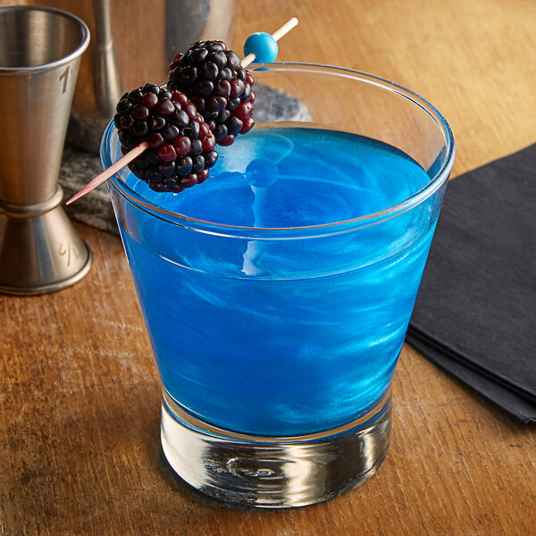 A blue cocktail with blackberries on a stick.