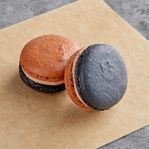 Two Macaron Centrale chocolate caramel macarons on a brown paper.
