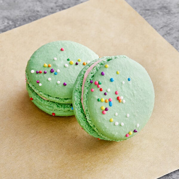 Two green Macaron Centrale macarons with sprinkles on top.