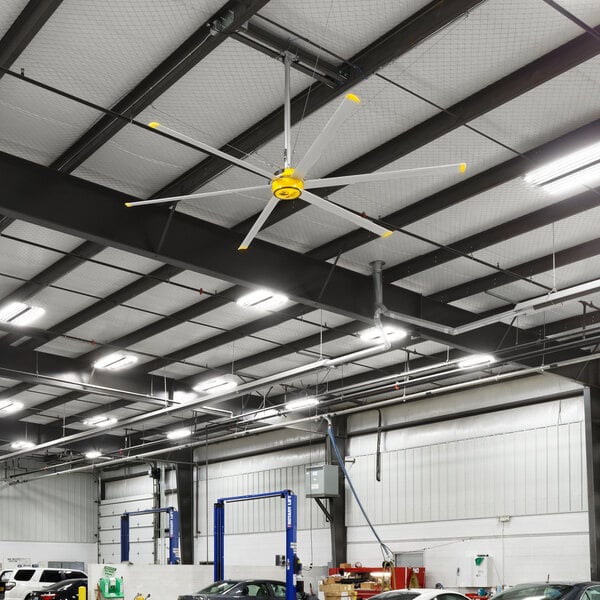 A Big Ass Fans yellow and silver ceiling fan in a building with cars.