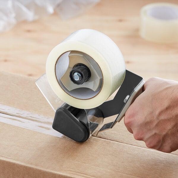 A hand using a Lavex tape dispenser to tape a box.