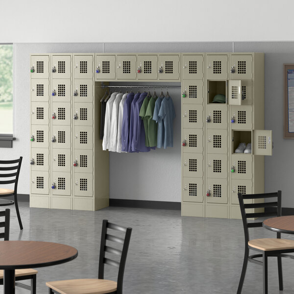 A room with Regency beige lockers and a garment rack with several shirts hanging.