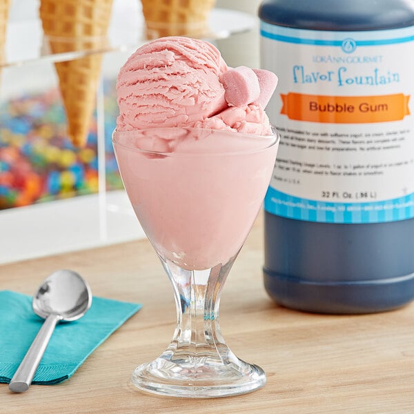 A glass of pink ice cream next to a bottle of LorAnn Bubble Gum Flavor Fountain syrup.