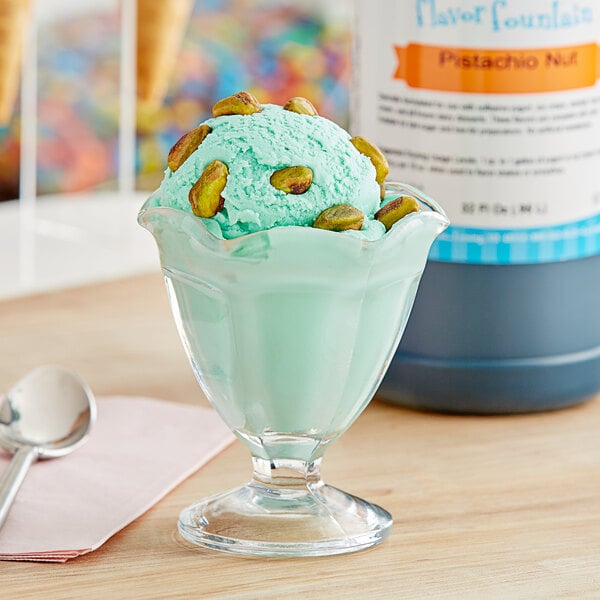 A glass cup of green pistachio ice cream with a spoon.
