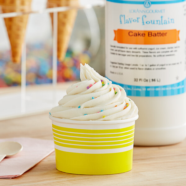 A cup of ice cream with sprinkles in front of a bottle of LorAnn Cake Batter Flavor syrup.