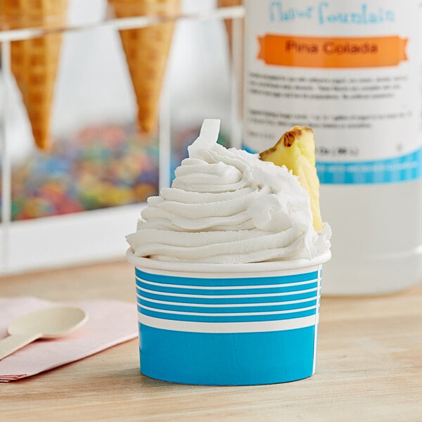 A cup of frozen yogurt with a pineapple slice in it using LorAnn Pina Colada Flavor Fountain syrup.