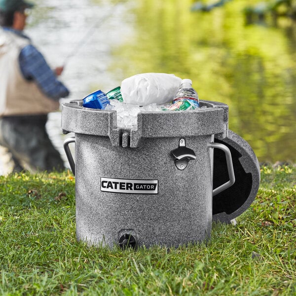 A grey CaterGator outdoor cooler with ice and plastic bottles in it.