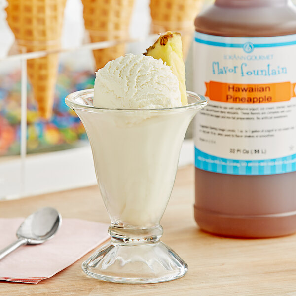A glass of ice cream with Hawaiian pineapple syrup and a pineapple slice on top.