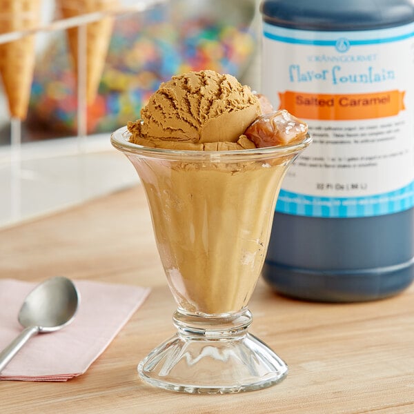 A glass of ice cream with a spoon and LorAnn Salted Caramel syrup on a counter.