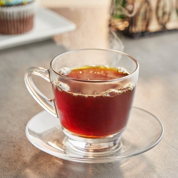 A glass cup of Crown Beverages Organic Colombian Coffee on a saucer.