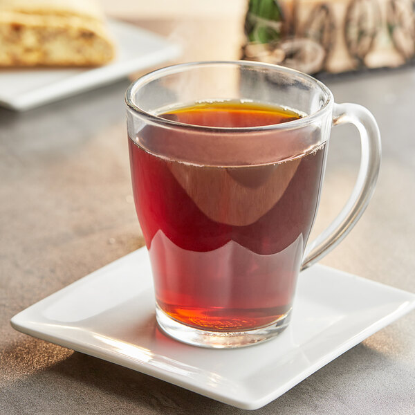 A glass cup of brown Crown Beverages Organic French Roast Coffee on a saucer.