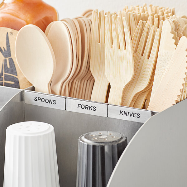 A silver container of ServSense stainless steel flatware labels with wooden spoons and forks.