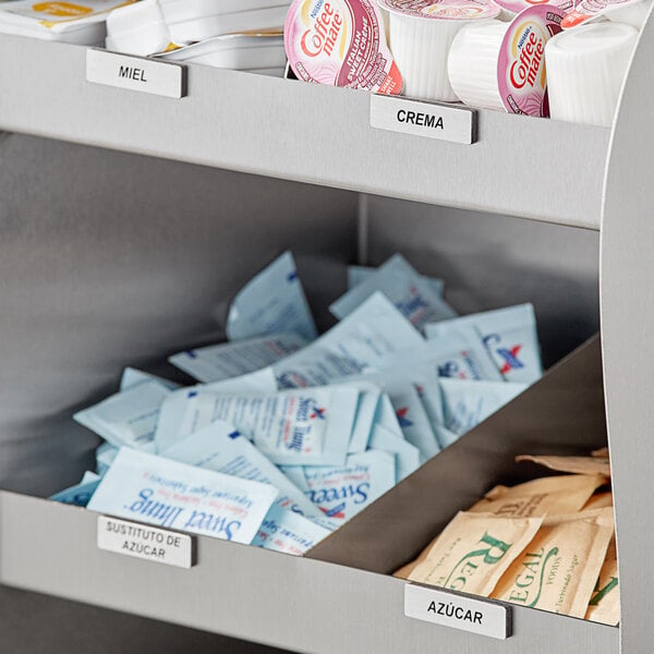 A metal shelf with stainless steel coffee labels in a container on a counter.