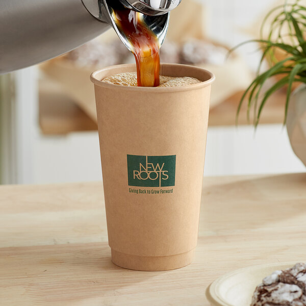 A New Roots double wall compostable paper hot cup being filled with coffee.