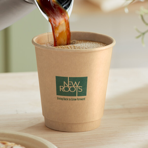 A person pouring coffee into a New Roots smooth double wall kraft paper hot cup.