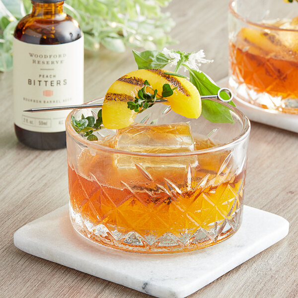A Woodford Reserve Peach Bitters drink garnished with a peach slice.