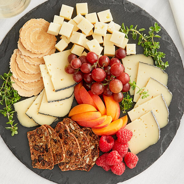A plate of cheese and fruit on a table at a catering event.