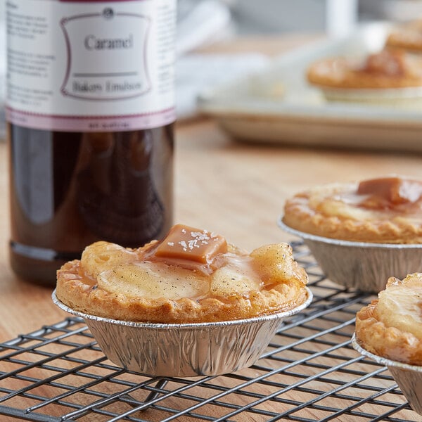 A close-up of a pastry with a bottle of LorAnn Oils Caramel Bakery Emulsion on a table in a bakery display.